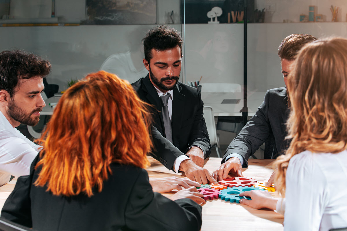 Business team connecting puzzle pieces, illustrating teamwork and partnership in Six Sigma implementation.