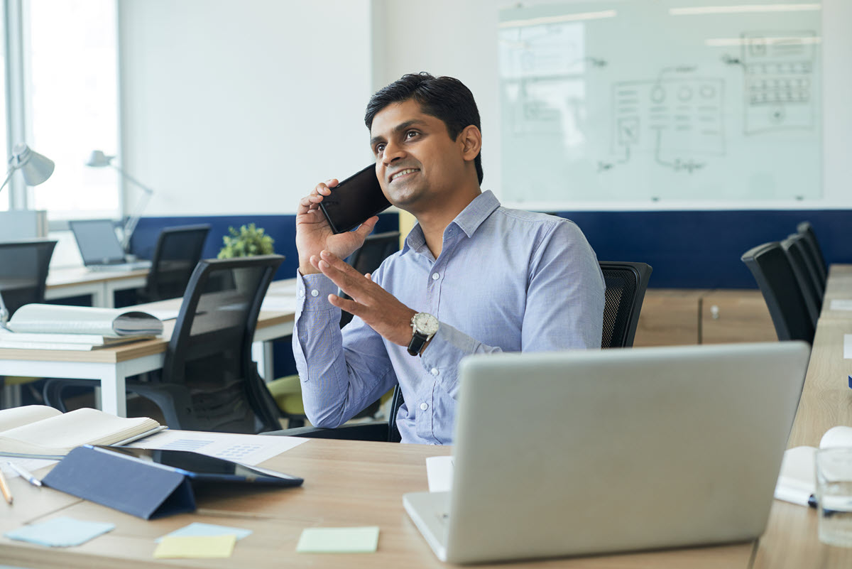 Smiling Six Sigma project manager discussing project details on the phone