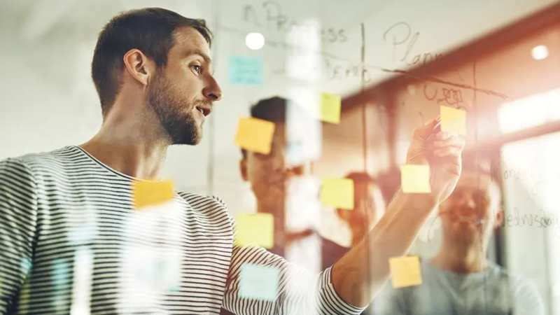 A team of professionals brainstorming Lean Six Sigma ideas using post-it notes on a wall.