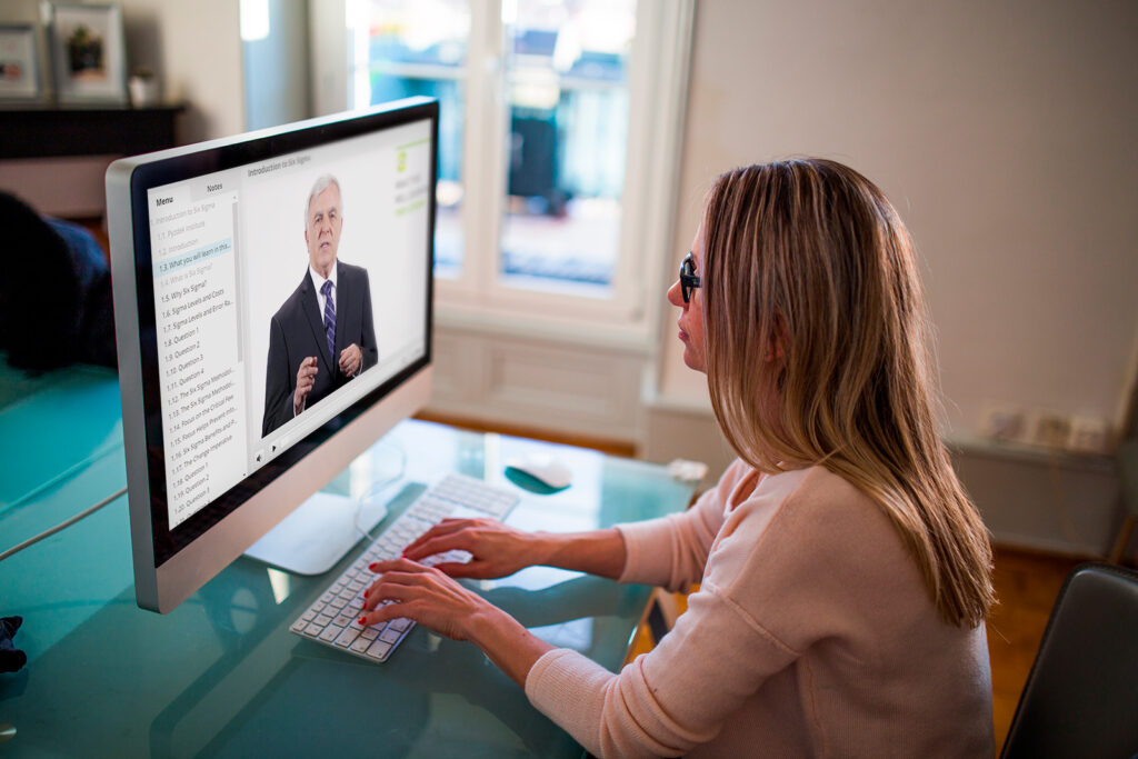 Woman actively engaged in the Lean Six Sigma Green Belt course, seated at her desk, studying on her computer with a clean and tidy workspace.