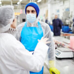 Man and woman engaged in a discussion about food quality in a food processing plant, representing the "Cost Reduction methods for Food Processing" course, focused on optimizing processes and reducing costs while upholding food safety and quality standards.