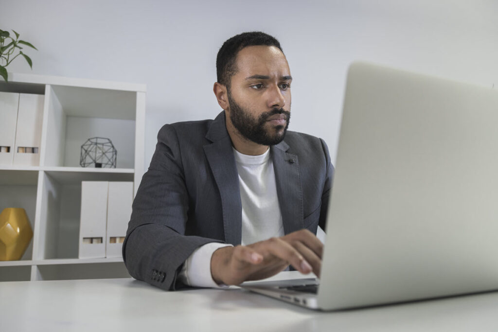 African American man in casual business attire working on Lean Six Sigma White Belt Training on his computer, learning the fundamental concepts and tools to improve processes.