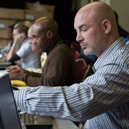Government professionals working together on laptops during a Lean Six Sigma training session, focused on improving public sector operations.